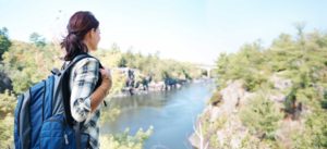 Young woman hikes in hills overlooking a river